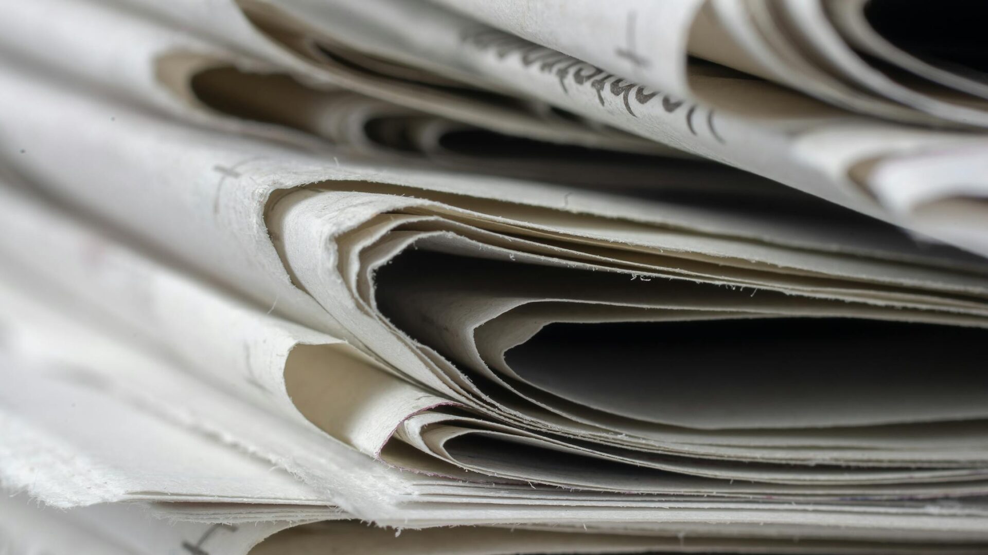 A detailed close-up view of stacked newspapers, highlighting textures and layers.